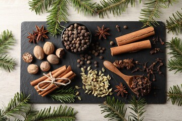 Different spices and fir branches on wooden table, flat lay