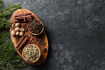 Different spices and fir branches on dark gray table, flat lay. Space for text