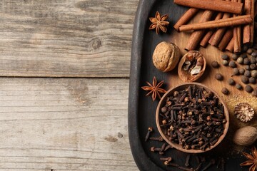 Different spices and nuts on wooden table, top view. Space for text