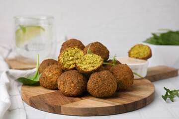 Delicious falafel balls, herbs and sauce on white tiled table