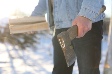 Man with axe and wood outdoors on sunny winter day, closeup
