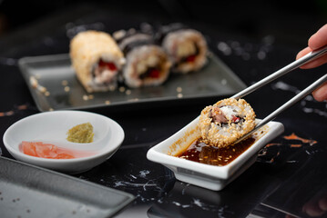 Close up of hands with chopsticks eating japanese food. Traditional asian rolls. Maki sushi with vegetables and tuna