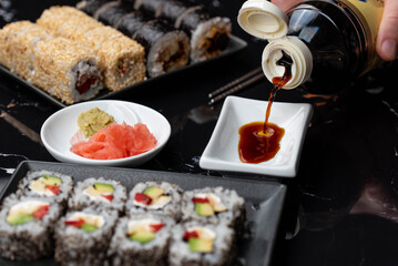 Close up of hands with chopsticks eating japanese food. Traditional asian rolls. Maki sushi with vegetables and tuna