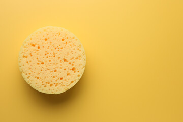 Sponge on yellow background, top view. Space for text
