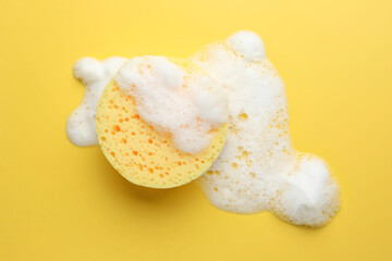 Sponge with foam on yellow background, top view