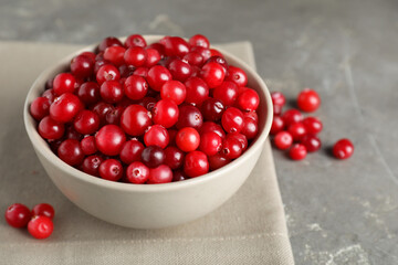 Cranberries in bowl on light grey table, closeup