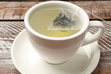 Tea bag in cup with hot drink on wooden rustic table, closeup