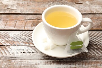 Tea bags and cup of aromatic drink on wooden rustic table, closeup. Space for text