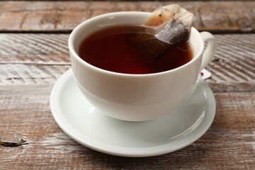 Tea bag in cup with hot drink on wooden rustic table, closeup