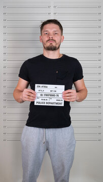 Brunette caucasian man standing with criminal mugshot letter board at police department