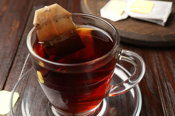 Brewing tea. Glass cup with tea bag on wooden table, closeup