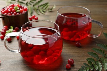 Tasty hot cranberry tea in glasses and fresh berries on wooden table