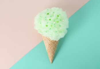 Sweet cotton candy in waffle cone on color background, top view