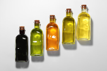 Vegetable fats. Different cooking oils in glass bottles on white background, flat lay