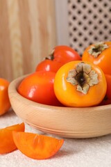 Delicious ripe persimmons on light textured table indoors