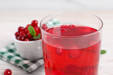 Tasty cranberry juice in glass on white table, closeup
