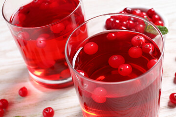 Tasty cranberry juice in glasses and fresh berries on white wooden table, closeup