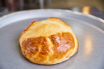 Golden Brioche Bun on Metallic Tray, Close-Up View