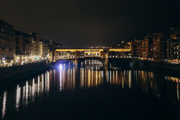 The Ponte Vecchio at night, a medieval stone closed-spandrel segmental arch bridge over the Arno, in Florence, Italy