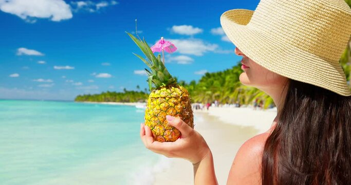 Woman with hat and pina colada cocktail enjoying caribbean life on tropical island beach, exotic summer vacation