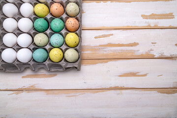 Packing of white chicken eggs next to Easter eggs. View from above. Space for text.