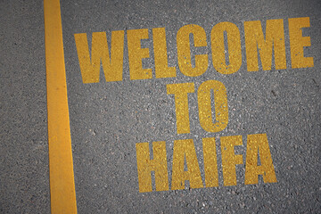 asphalt road with text welcome to Haifa near yellow line.