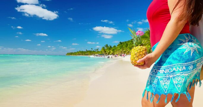 Woman in swimsuit and pina colada cocktail enjoying caribbean summer vacation on a tropical island beach in Dominican Republic