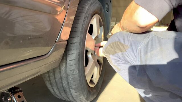 Close up of an unrecognizable mechanic removing the flat tire of a car