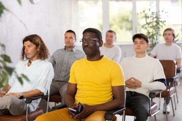 Portrait of focused African American man participating study session, sitting in auditorium with...