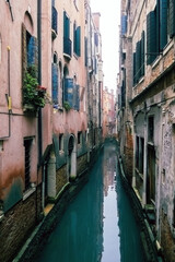 Small waterways of Venice. River canal with old colorful buildings in foggy day, Italy. Typical boat transportation. Venetian travel urban scene. Water transport. Popular tourist destination.