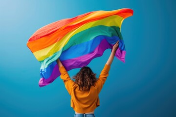 young proud lesbian woman spreading wide big pride homosexual flag with his shadow behind the cloth in defending equality and diversity standing for the human rights - obrazy, fototapety, plakaty
