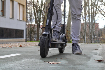 Legs on an electric scooter, front view, standing, unrecognizable, on an enabled lane