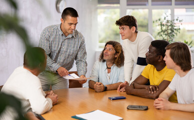 Group of men gathered in the audience at a conference, discussing something at the desk