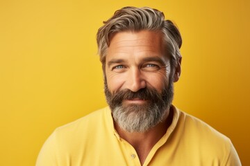 Portrait of handsome mature man with long gray beard and mustache. Studio shot on yellow background.