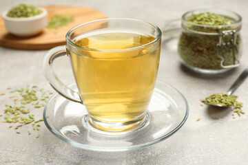 Aromatic fennel tea and seeds on light grey table, closeup