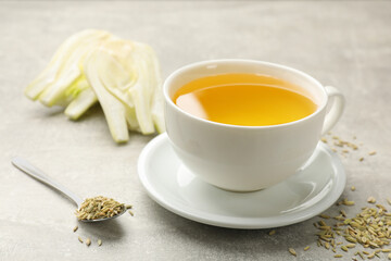 Aromatic fennel tea, seeds and fresh vegetable on grey table, closeup. Space for text