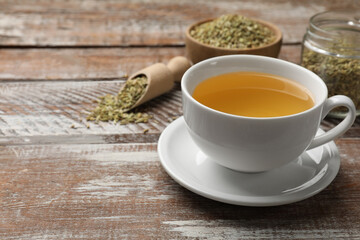 Aromatic fennel tea in cup and seeds on wooden table, closeup. Space for text