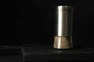Pepper shaker on black table. Space for text
