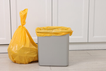 Plastic garbage bag and trash can indoors
