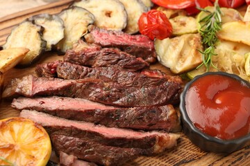 Delicious grilled beef with vegetables, tomato sauce and spices on table, closeup