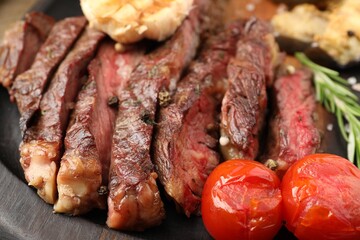 Delicious grilled beef with tomatoes and spices on tray, closeup
