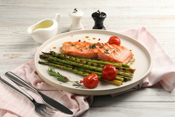 Tasty grilled salmon with tomatoes, asparagus and spices served on table