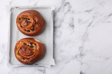 Delicious rolls with raisins on white marble table, top view and space for text. Sweet buns