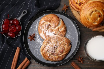 Delicious rolls with sugar powder, berries and spices on wooden table, flat lay. Sweet buns