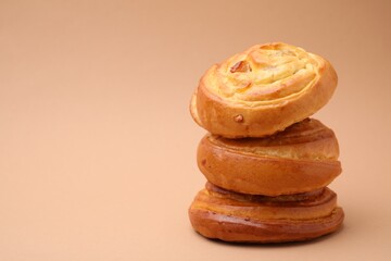 Stack of delicious rolls with raisins on beige background, space for text. Sweet buns