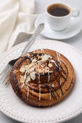 Delicious roll with poppy seeds, topping and fork served on light table, closeup. Sweet bun
