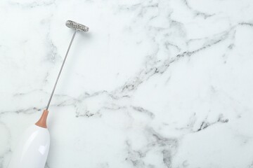 Milk frother wand on white marble table, top view. Space for text