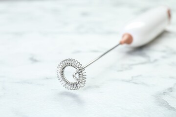 Milk frother wand on white marble table, closeup