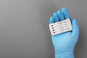 Doctor holding disposable multi-infection express test on light grey background, top view. Space...