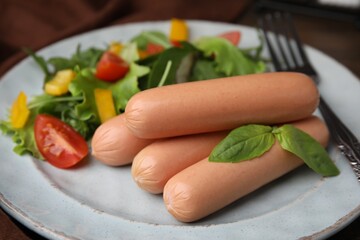 Delicious boiled sausages with salad on table, closeup